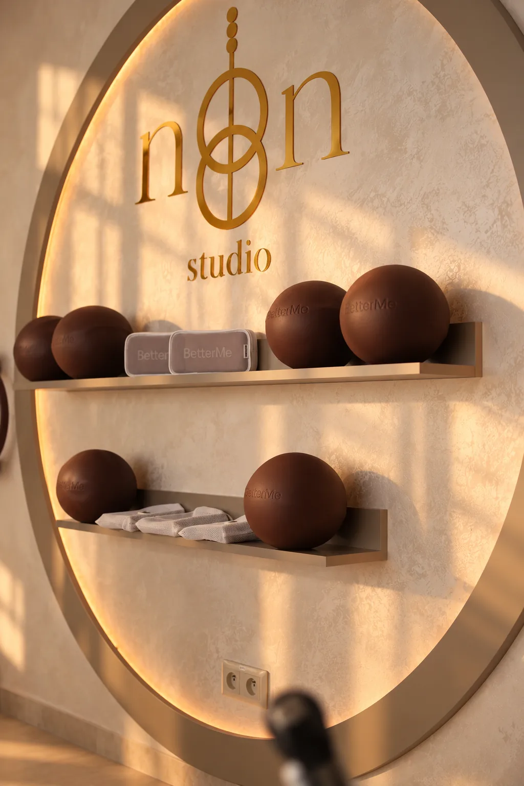 Zlatý kruhový výklenok so studiovými pomôckami a logom NOON STUDIO